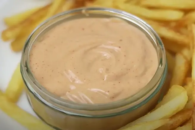 Zaxby’s Tongue Torch Sauce served in a glass bowl with crispy French fries on the side, a creamy and spicy dipping sauce perfect for pairing with fast food.