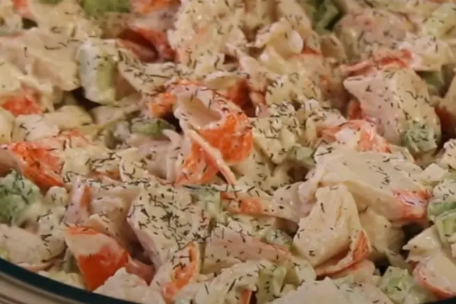 Close-up of creamy Golden Corral crab salad showing chunks of crab meat mixed with diced celery, carrots, and sprinkled with dried dill herbs in a glass bowl.