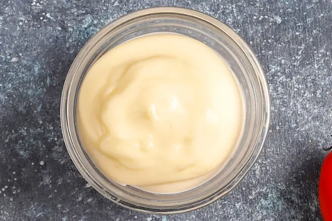 Glass bowl of creamy Sonic Signature Sauce on a dark textured background