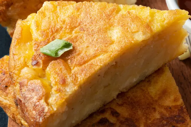 Close-up of a golden, fluffy White Lily cornbread slice with crispy crust and garnish, served on a wooden board