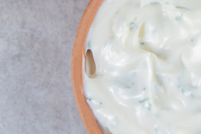 Close-up of creamy Wingstop blue cheese dip with herbs in a terracotta bowl on a stone surface